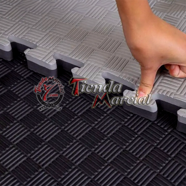 Detalle del sistema de encaje tipo rompecabezas de un tatami EVA de alta densidad de 2.5 cm de grosor en color negro y gris, ideal para artes marciales, gimnasios, defensa personal y áreas deportivas.