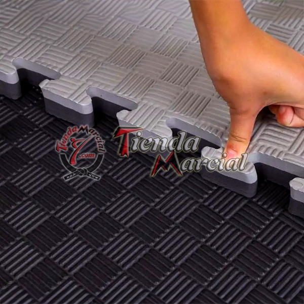 Detalle del sistema de encaje tipo rompecabezas de un tatami EVA de alta densidad de 4 cms de grosor en color negro y gris, ideal para judo, aikido, jiu jitsu y disciplinas con proyecciones.